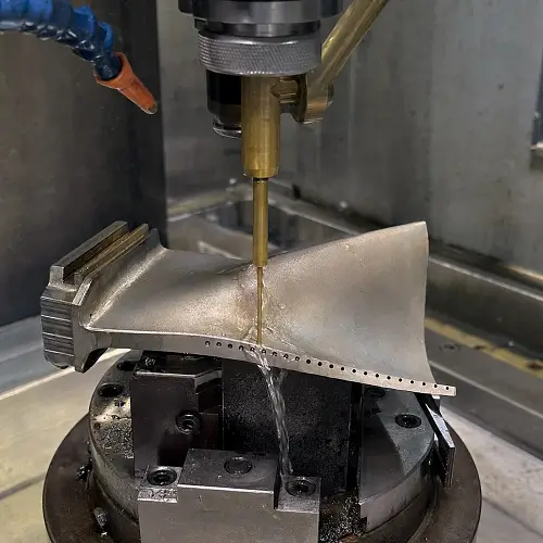 Hole drilling EDM producing cooling holes in a nickel alloy turbine blade